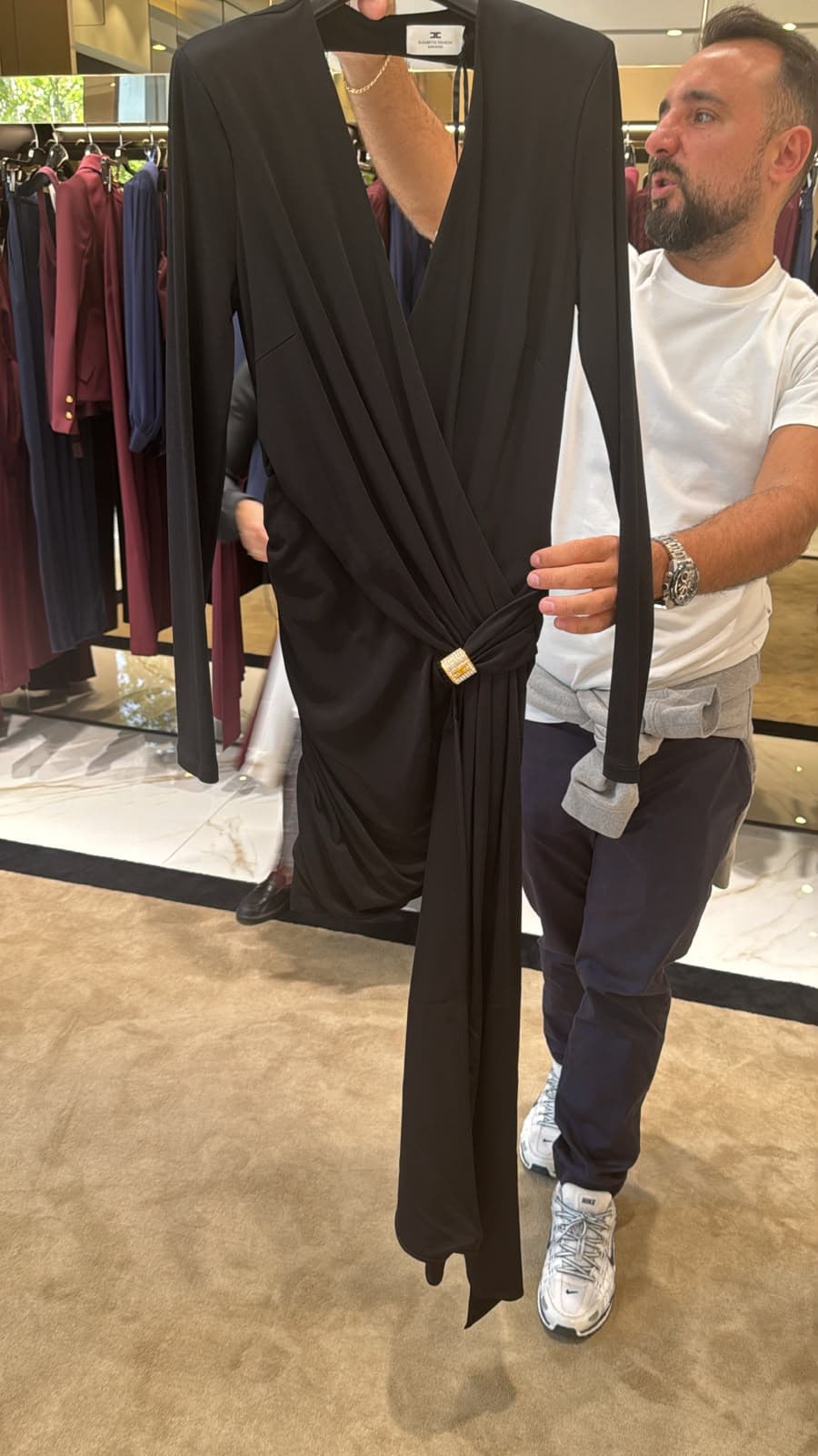 Vestido negro drapeado con broche dorado